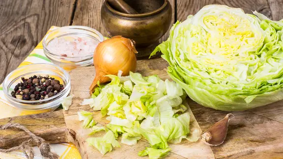 Klein geschnittener Weißkohl auf einem Holzbrett, daneben eine Zwiebel und Gewürze. | Colourbox Klein geschnittener Weißkohl auf einem Holzbrett, daneben eine Zwiebel und Gewürze.