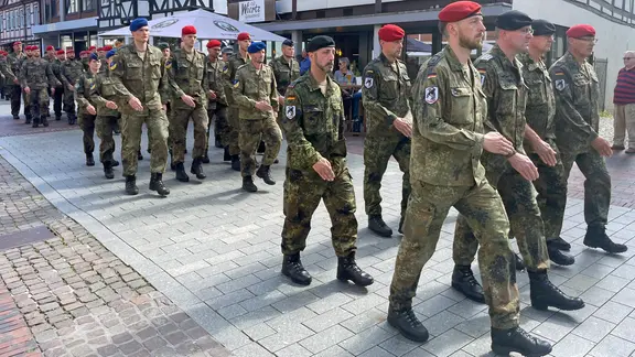 Soldaten marschieren durch ein Stadtzentrum.