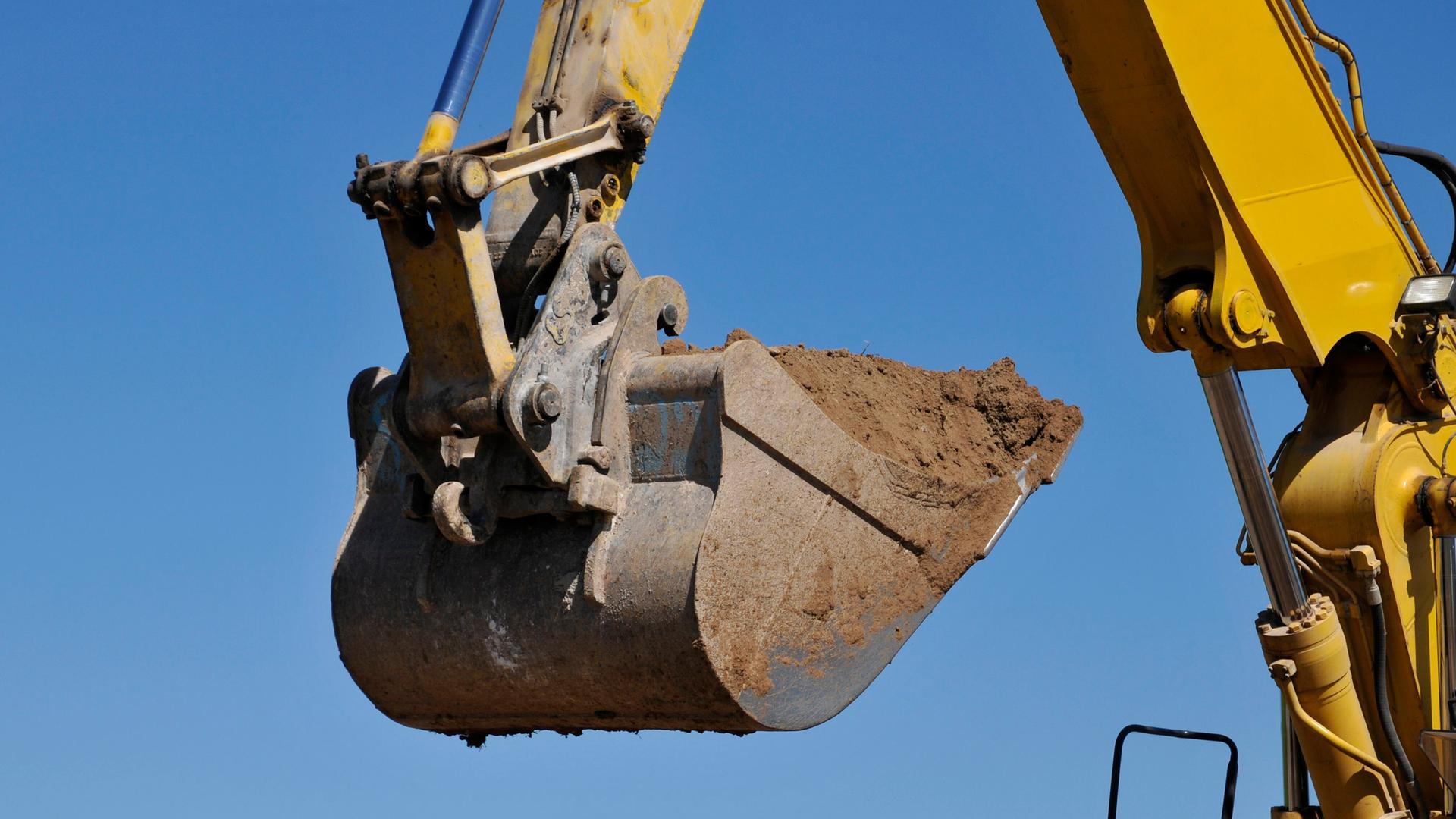 Ein Bagger transportiert Erde in seiner Schaufel. | picture alliance / CHROMORANGE / Dieter Möbus