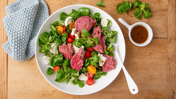 Ein Teller mit Rote-Bete-Knödeln, Tomaten, Ziegenkäse und Salat