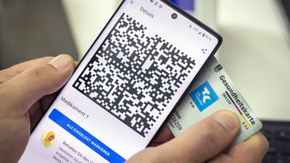 Jemand zeigt sein Smartphone mit einem elektronischen Rezept und eine Krankenkassenkarte.