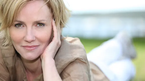 Eine reife Frau liegt auf Rasen