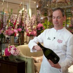 Küchenchef Christoph Rüffer öffnet eine Flasche Champagner.