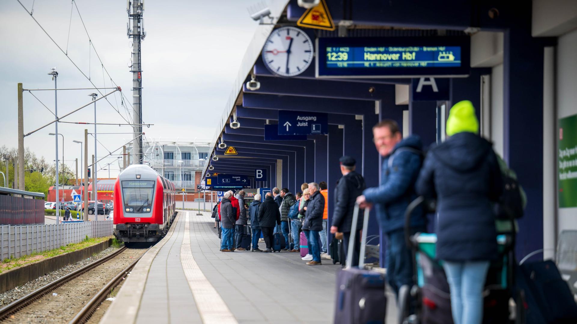 Touristen laufen mit Rollkoffern am Bahnhof Norddeich-Mole entlang. | Sina Schuldt, dpa