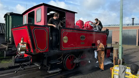 Drei Männer putzen eine historische Bahn.