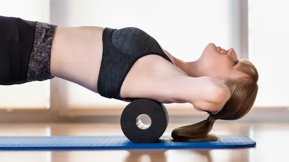 Eine Frau trainiert auf einer Faszienrolle