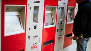 Eine Person bedient im Hauptbahnhof Hannover einen von drei Fahrkartenautomaten.