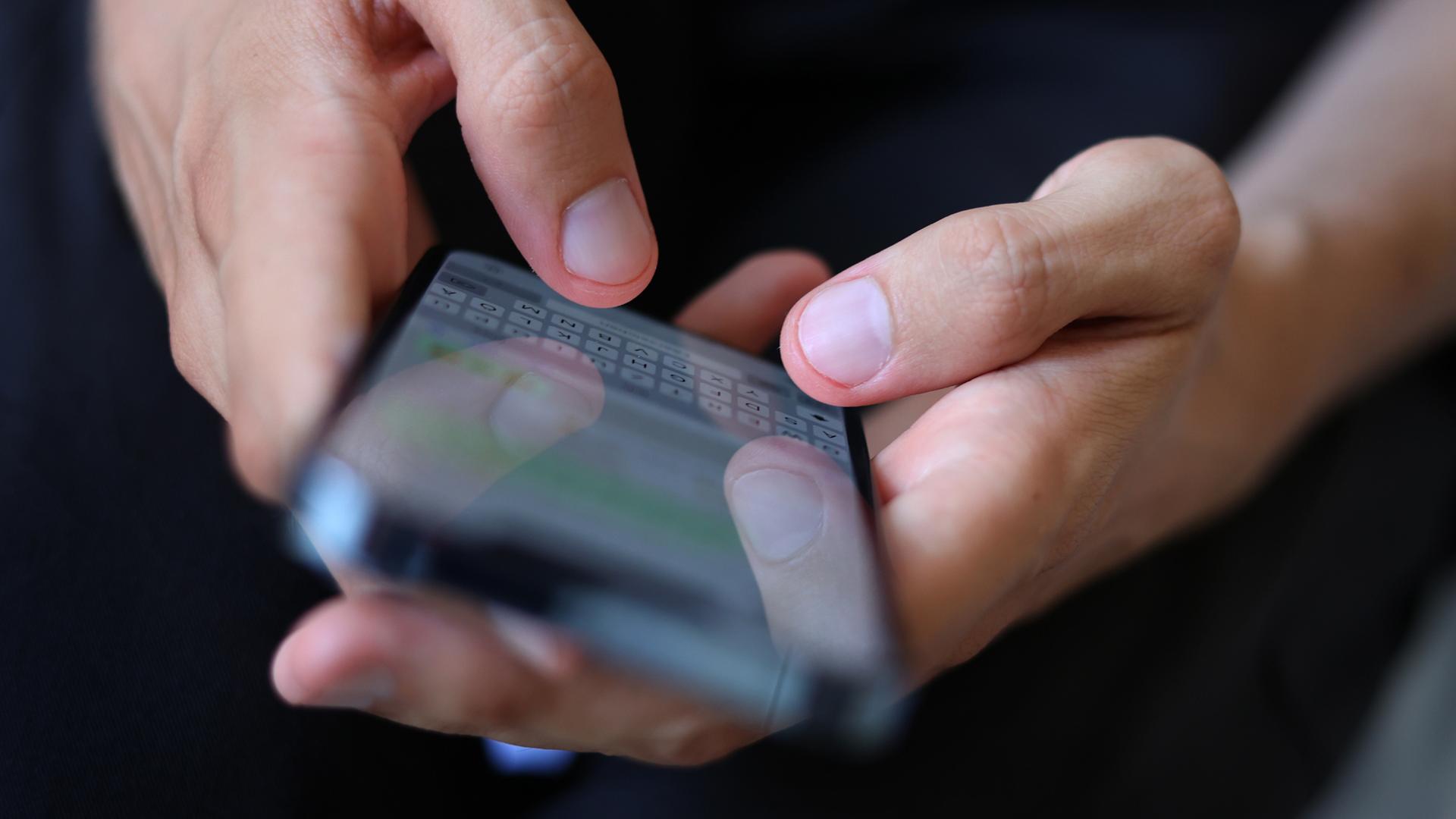 Ein junger Mann tippt auf einem Smartphone eine WhatsApp-Nachricht. | picture alliance/dpa, Karl-Josef Hildenbrand