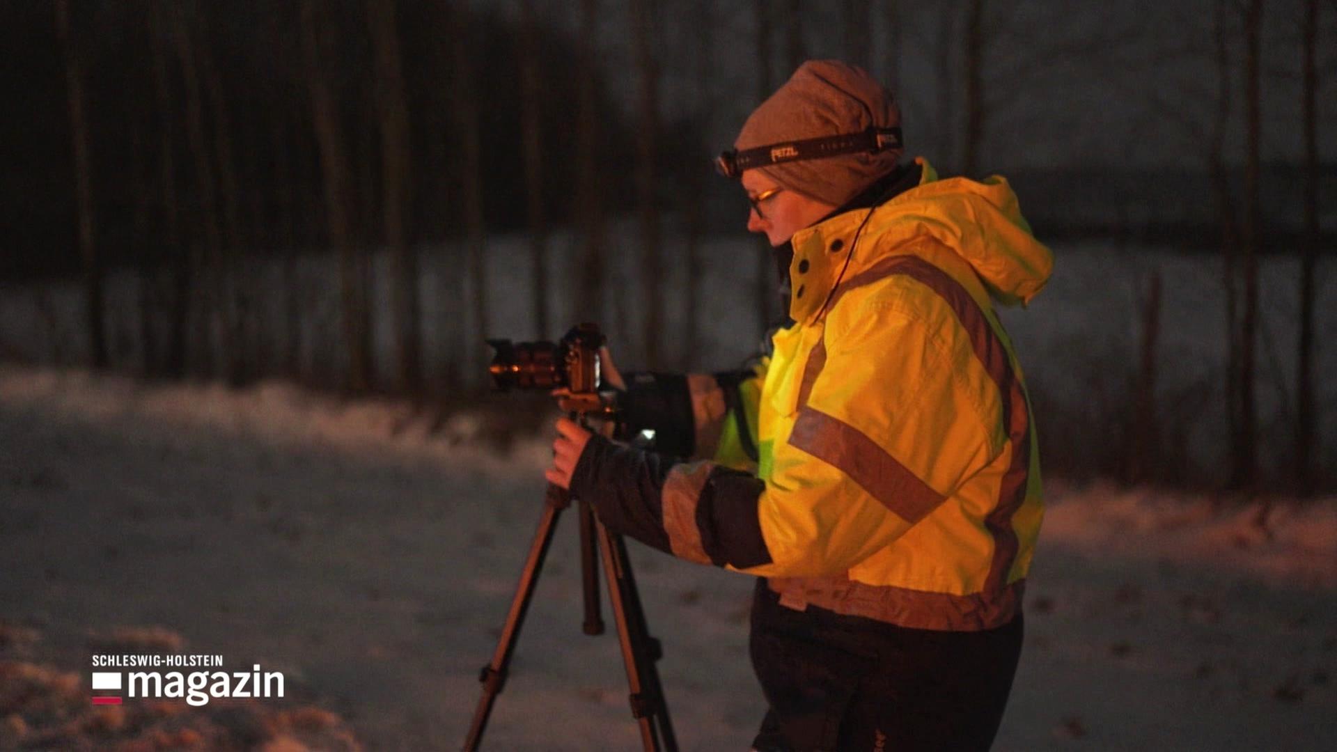 Eine Person mit einer Kamera im Dunkeln. | Screenshot