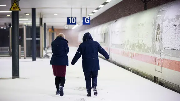 Zwei Bahn-Mitarbeiterinnen gehen am frühen Morgen an einem ICE im Hauptbahnhof entlang.
