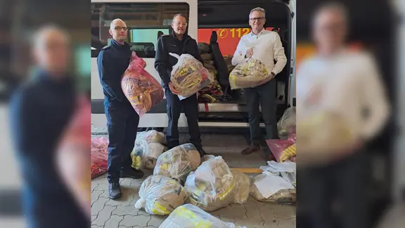 Drei Männer halten Spenden der FF Henstedt-Ulzburg in den Händen.