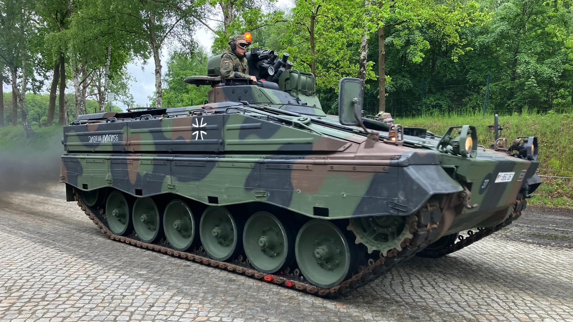 Ein Mensch sitzt in Bundeswehruniform mit Schutzbrille auf einem Panzer in Bergen. | NDR, Simon Schmidt