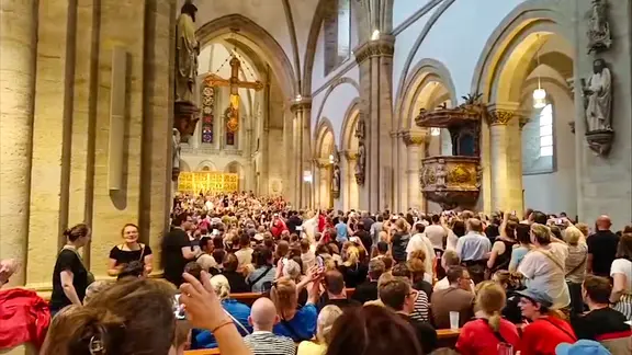 Besucher einen Konzertes, das wegen schlechten Wetters abgebrochen wurde, feiern im Osnabrücker Dom weiter.