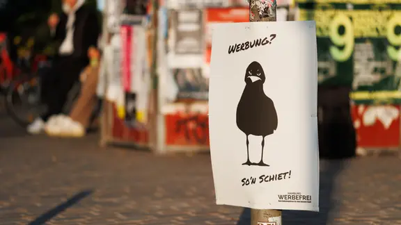 Werbung für das Volksbegehren "Hamburg Werbefrei" vor anderen Werbeplakaten.