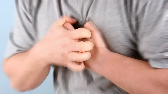 Ein Mann greift sich mit beiden Händen an den Brustkorb.