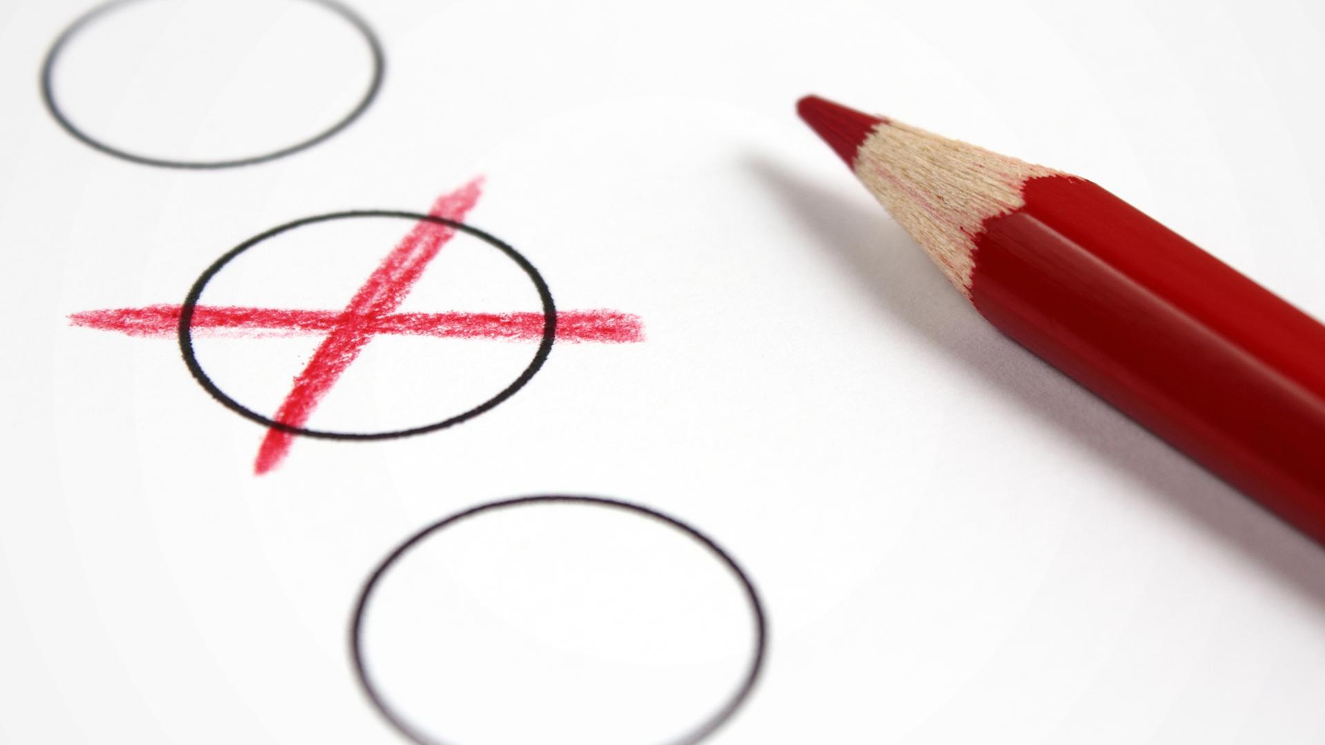 Ein rotes Wahlkreuz neben einem roten Buntstift. | fotolia, Patrick M. Pelz