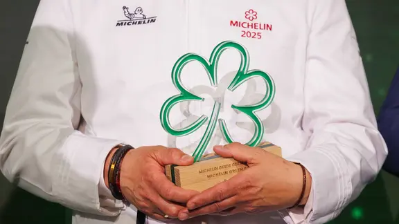 Ein Sternekoch hält eine Michelin-Auzeichnung in den Händen.