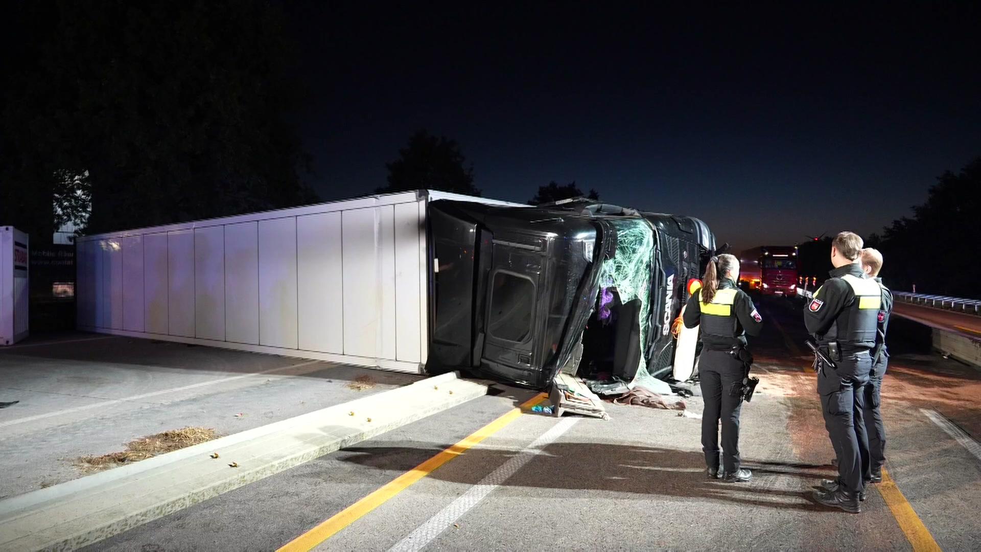 Polizisten stehen nach einem Unfall vor einem umgekippten Lkw auf der A1 bei Groß Ippener. | Nord-West-Media TV