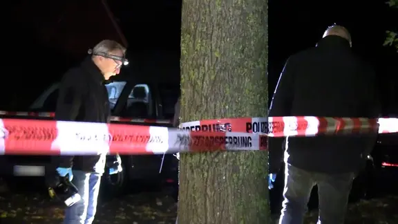 Beamten untersuchen einen Gehsteig vor einem Wohnhaus in Stade, aus dem ein Vater seine Tochter entführt hat.