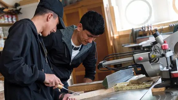 Zwei Flüchtlinge arbeiten in einer Holzwerkstatt.