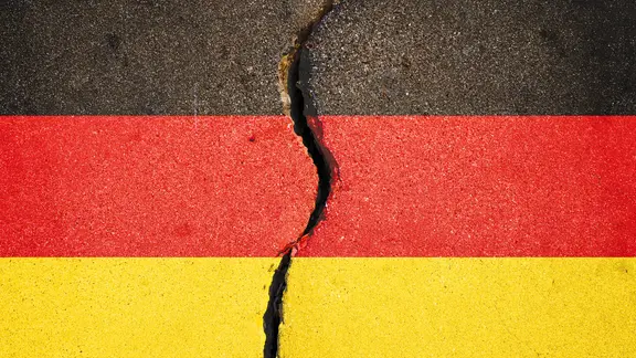 Die Farben Schwarz, Rot und Gold auf einem Steinboden mit einem Riss
