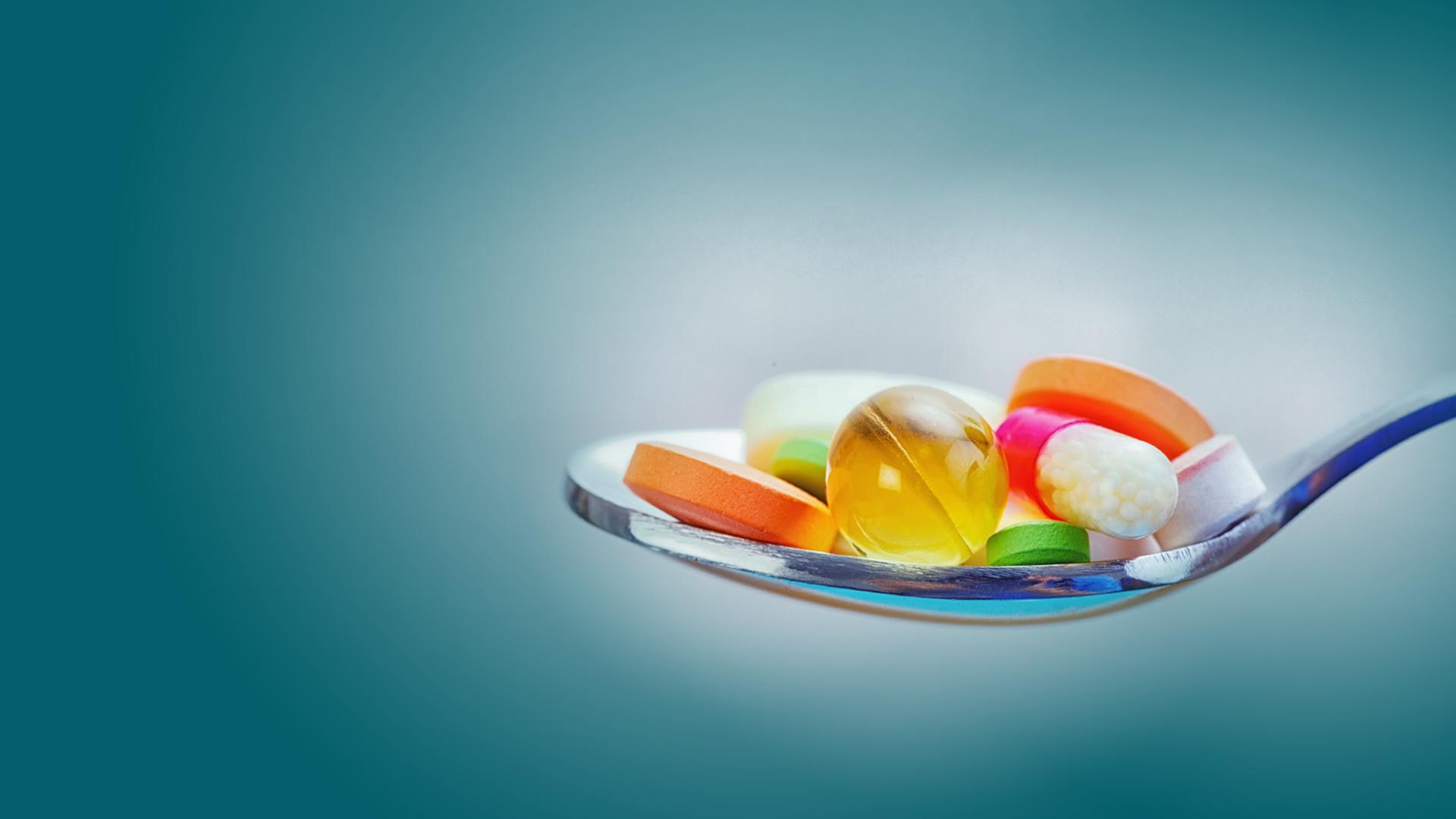 Ein Löffel mit verschiedenen bunten Pillen | smarterpix/Lighthunter