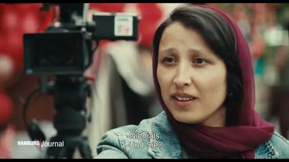 Eine Frau mit Kopftuch neben einer Kamera.