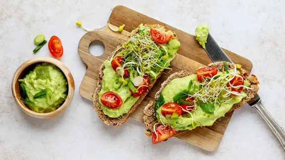 Zwei Scheiben Brot mit einer Erbsencreme, Tomaten und Sprossen. | ZS-Verlag, Claudia Timmann Zwei Scheiben Brot mit einer Erbsencreme, Tomaten und Sprossen.