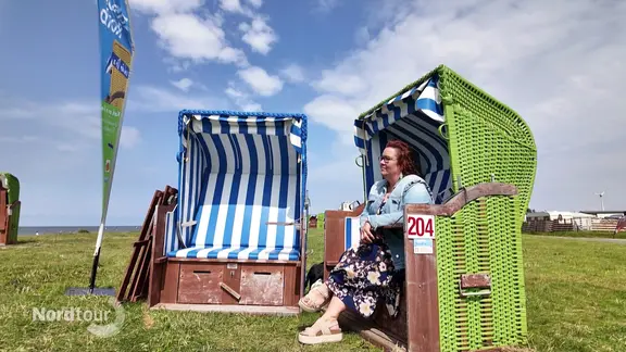 Zwei Strandkörbe stehen auf einer Wiese. In einem sitzt wartend Leona, die Zuhörerin.