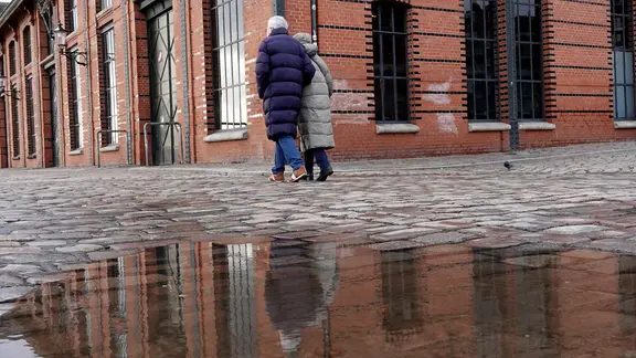 Passanten laufen über den nassen Parkplatz vor der Fischauktionshalle in Hamburg.