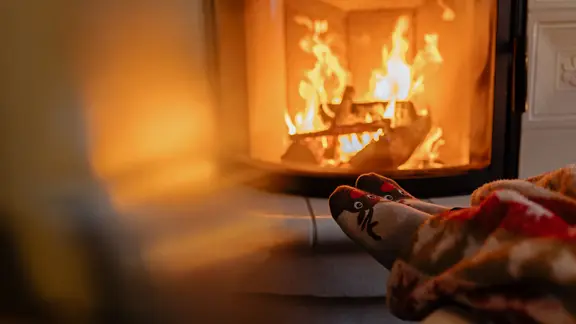 Eine Person sitzt mit warmen Socken vor einem Kaminofen.