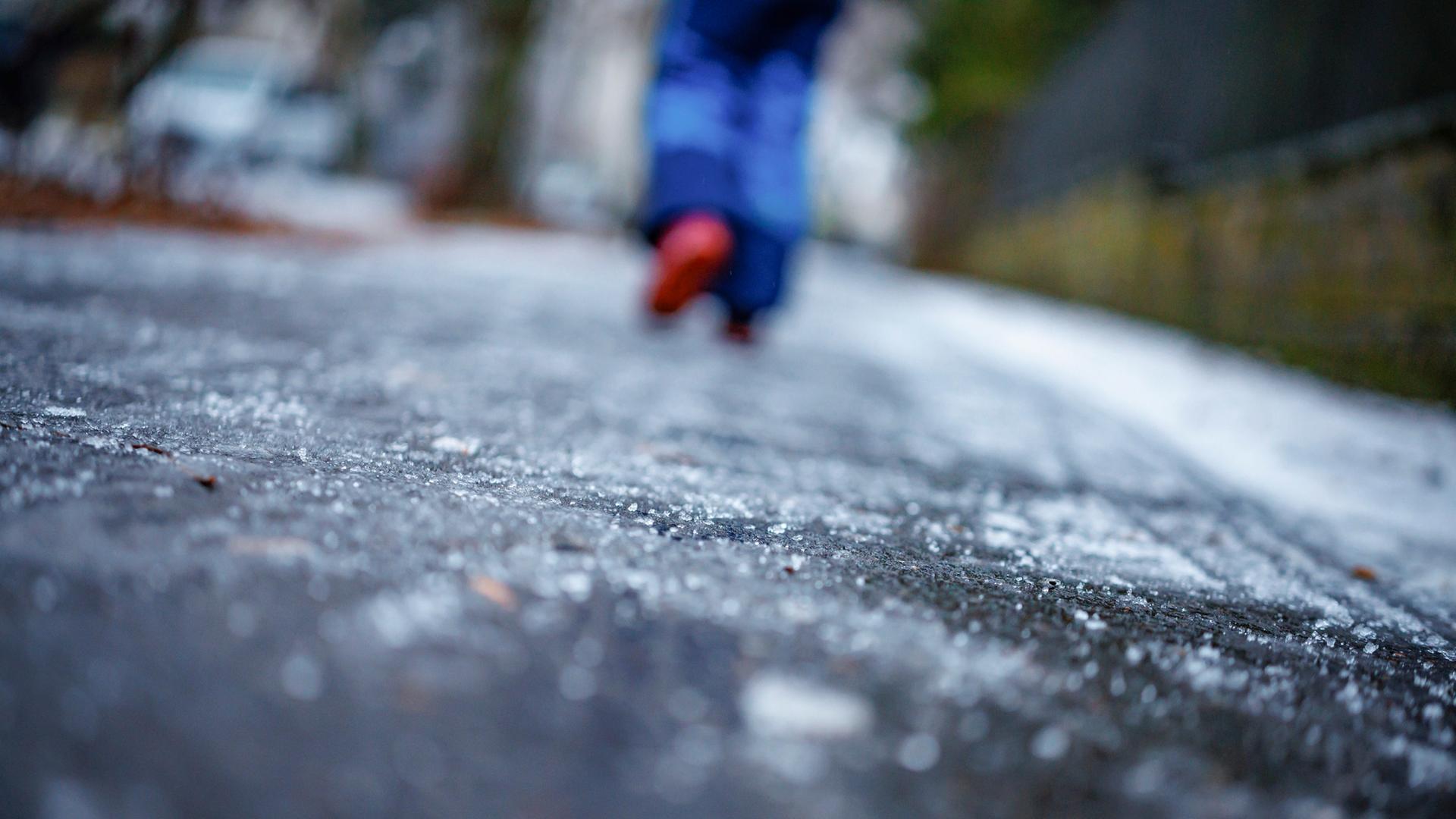 Eine Person läuft über einen durch gefrierenden Regen vereisten Gehweg. | picture alliance / photothek.de | Thomas Trutschel
