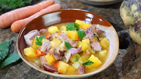 Steckrübeneintopf mit Kassler Rippe und Mettenden in einem Teller serviert