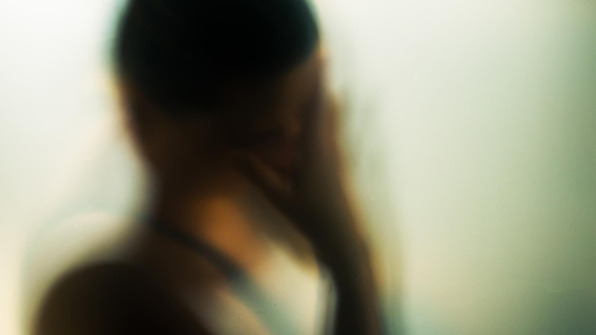 Ein unscharfer Kopf einer Person von hinten, die sich an den Kopf fasst. | Jeeni/Photocase Addicts GmbH