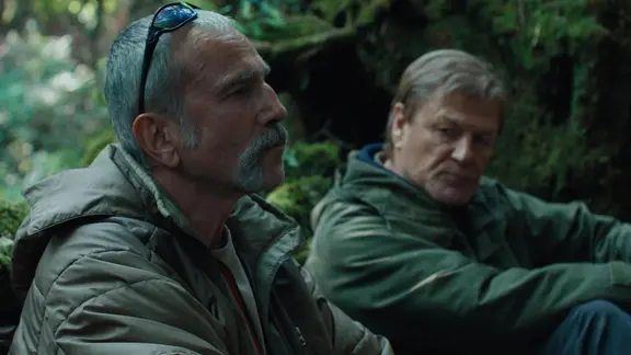 Szene aus dem Film "Anemone": Zwei ältere Männer sitzen nebeneinander im Wald