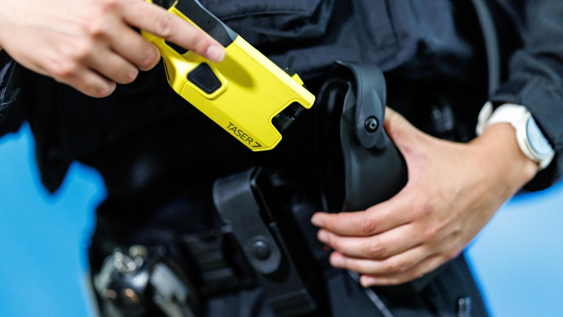 Eine Polizistin zieht eine Taser aus seiner Halterung. | picture alliance, Matthias Balk