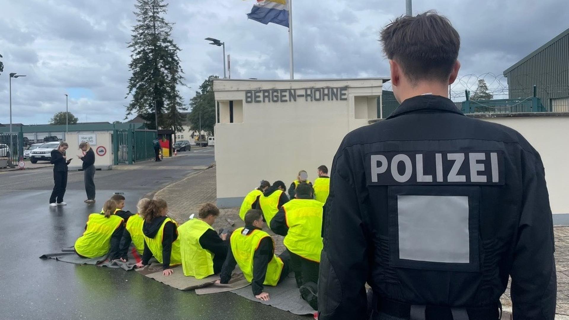 Ein Polizist steht vor Schauspielern, die Demonstranten im Sitzstreik simulieren.  | NDR, Luka Simon 