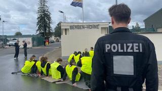 Ein Polizist steht vor Schauspielern, die Demonstranten im Sitzstreik simulieren.