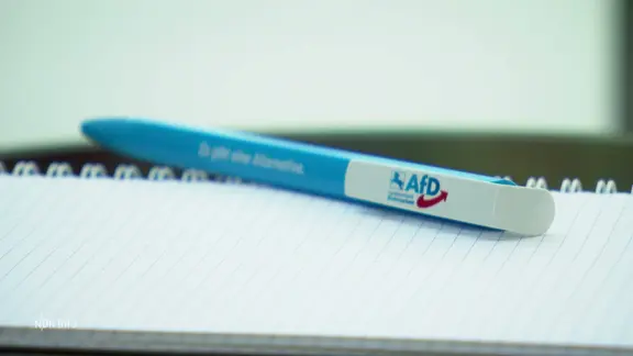 Auf einem Notizblock liegt ein Kugelschreiber mit AFD-Logo