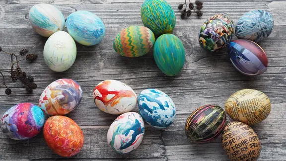 Variationen von selbst gestalteten Ostereiern liegen auf einer Fläche.