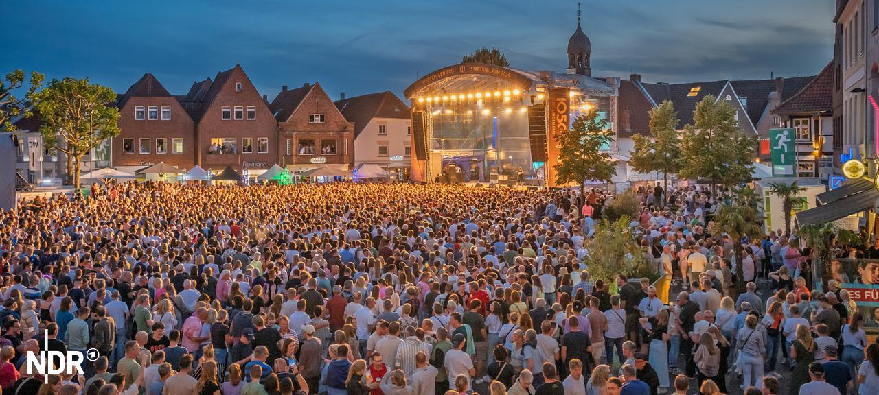 Eine Menschenmenge steht vor einer Bühne auf dem Marktplatz in Lingen. Es ist Abend. | Stadt Lingen Eine Menschenmenge steht vor einer Bühne auf dem Marktplatz in Lingen. Es ist Abend.
