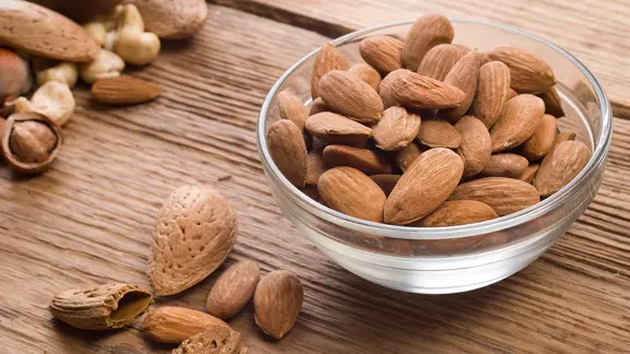 Mandelkerne in einer Glasschale sowie Nüsse und Schalen auf einer Holzplatte | colourbox Mandelkerne in einer Glasschale sowie Nüsse und Schalen auf einer Holzplatte
