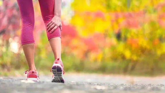 Magnesiummangel: Frau greift sich beim Laufen an schmerzende Wade