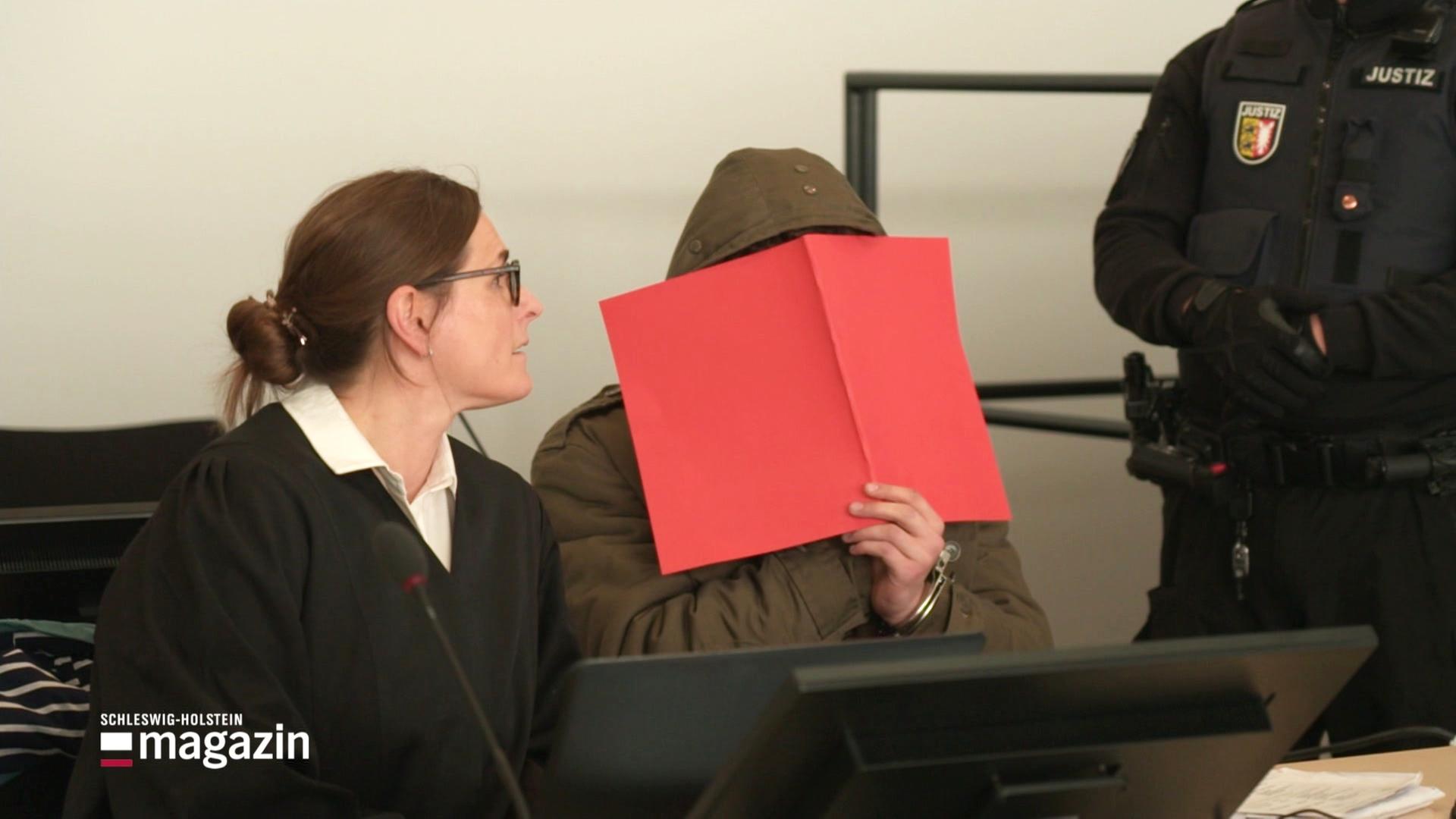 Der Angeklagte in einem Mordprozess versteck sein Gesicht hinter einer Mappe.  | Screenshot