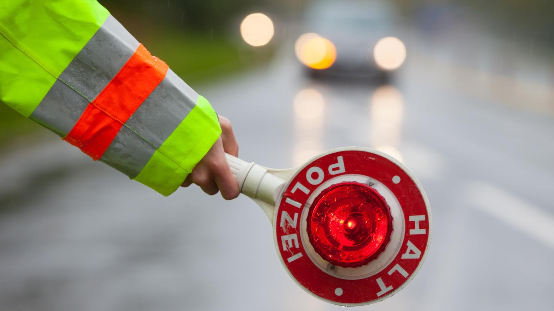 Polizist hält eine Kelle mit der Aufschrift 
